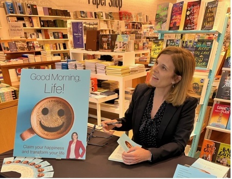 Barbara Demone signing a copy of Good Morning, Life! at a book signing event