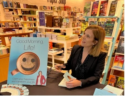 Barbara Demone signing a copy of Good Morning, Life! at a book signing event
